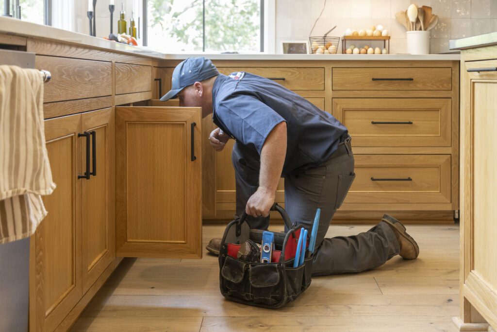 Plumber Fixing a Garbage Disposal Under a Kitchen Sink
