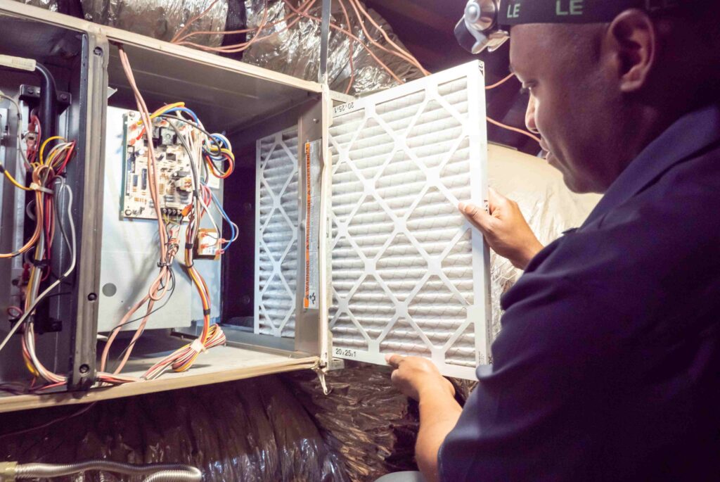 A Professional Replacing an Air Filter in a Furnace